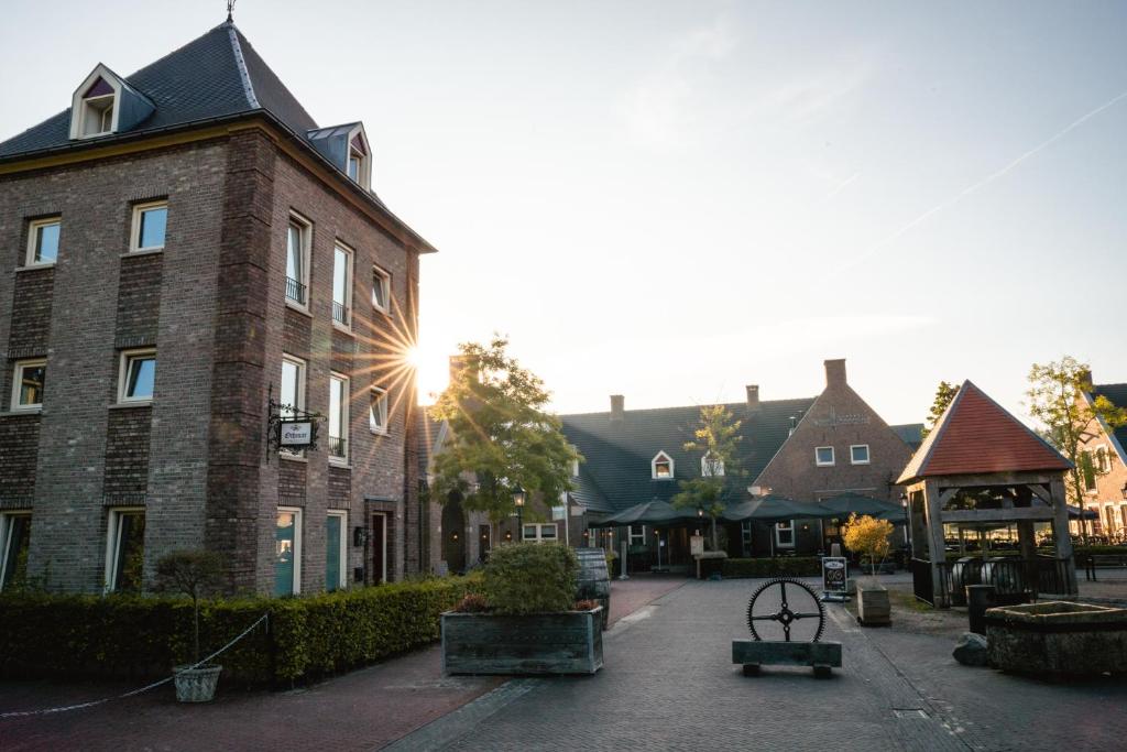 a brick building with the sun shining on a street at Othmar 't Lagerhuys - Groepsaccommodatie in Ootmarsum