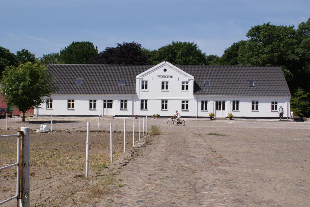 a person riding a bike in front of a white building at Holtegaard Bed & Breakfast in Dronninglund
