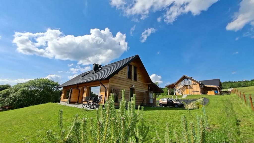 a house on a grassy hill with a car in front at Kuźnia Nowica in Uście Gorlickie