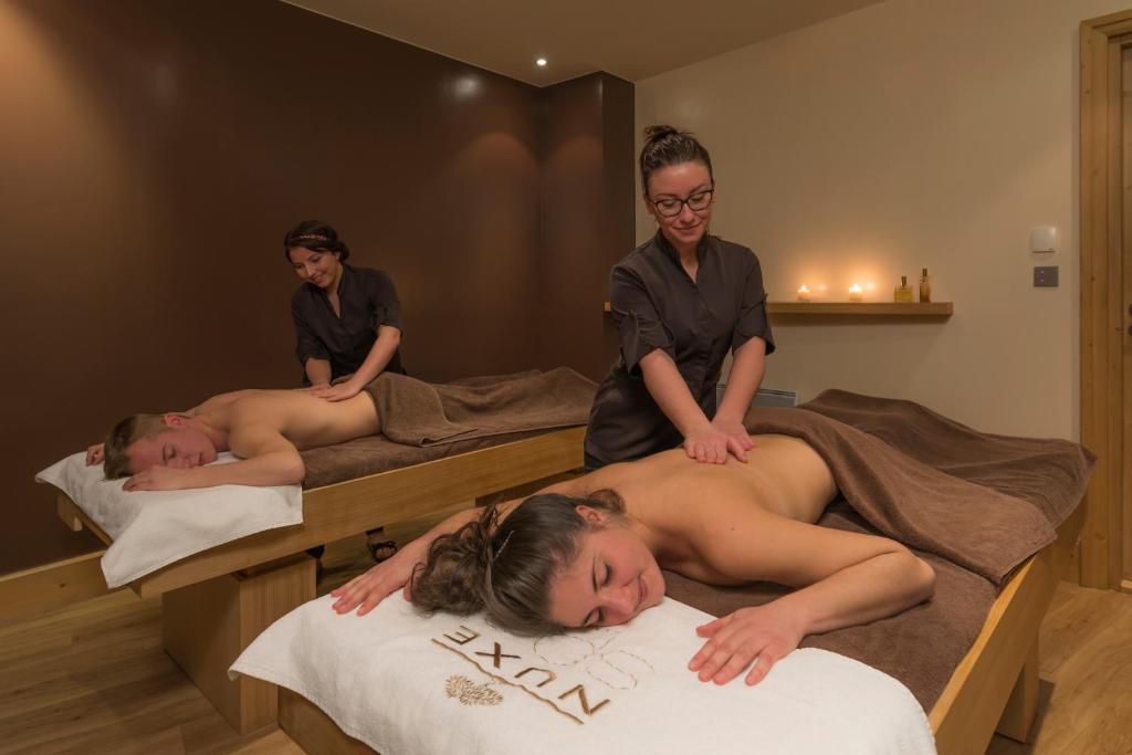 two people laying on beds in a massage room at Le Kaïla in Méribel