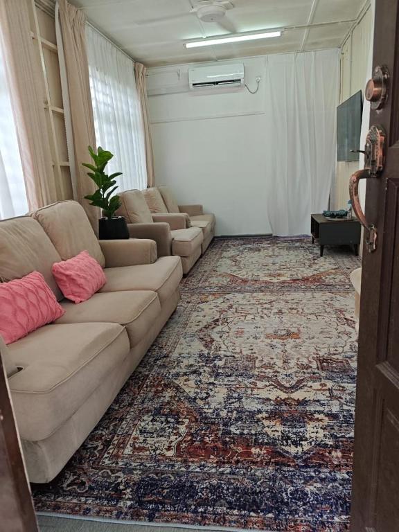 a living room with a couch and a rug at Rooma Kayu in Kampong Alor Fatimah