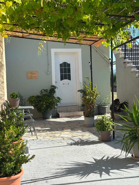 a patio with a white door and some plants at Maria's Apartment in Lixouri
