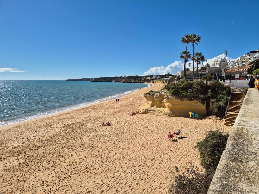 a beach with people laying on the sand and the ocean at CARAVELL ARMAÇÃO de PÊRA in Armação de Pêra