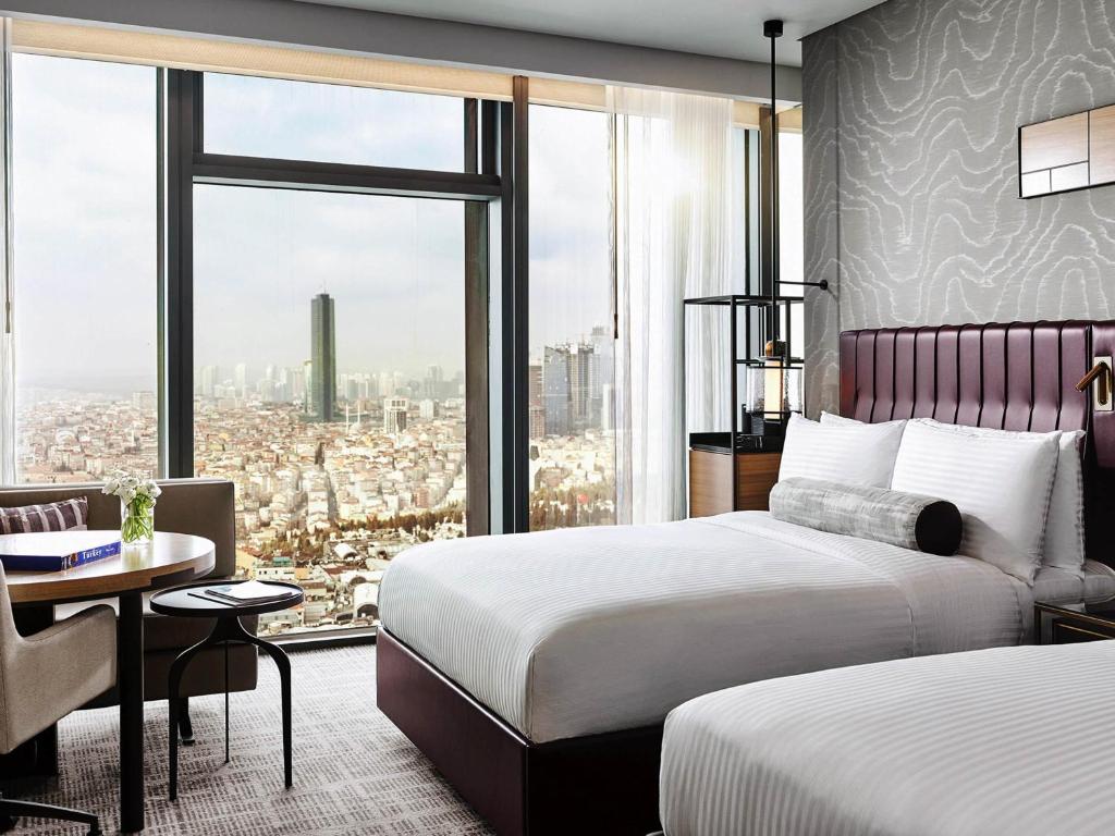 a hotel room with two beds and a large window at Fairmont Quasar Istanbul Hotel in Istanbul
