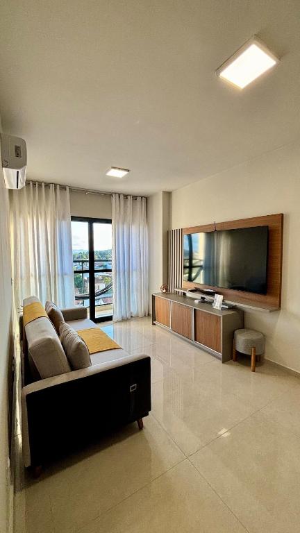 a living room with a couch and a flat screen tv at Apartamento completo Studio 9 centro Pouso Alegre in Pouso Alegre