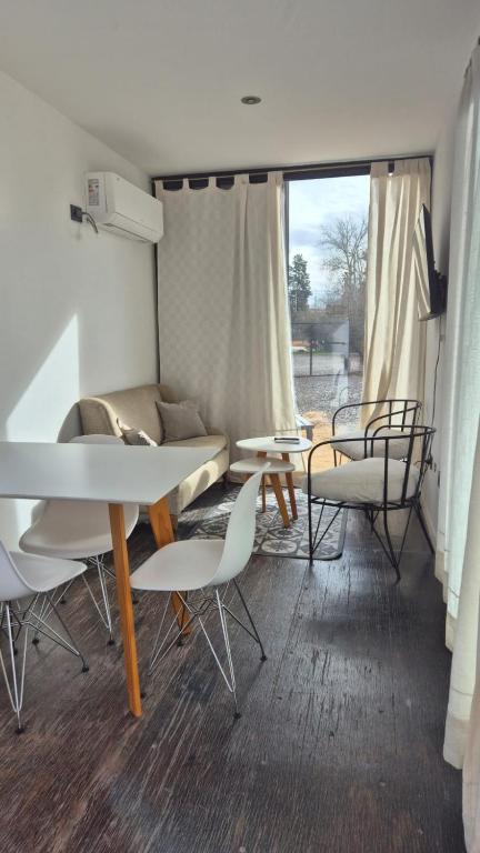 a living room with tables and chairs and a couch at Cubil Amarillo. Casa conteiner 1 dormitorio in General Roca