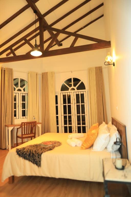 a bedroom with a large bed with white sheets and pillows at Mino Villa Kandy in Kandy