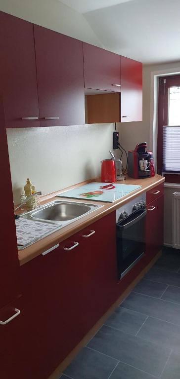 a kitchen with red cabinets and a sink at Ferienwohnung in Walsrode