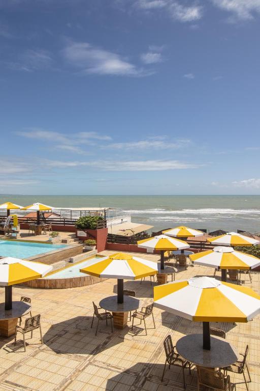 a group of tables and chairs with umbrellas on the beach at Pipas Ocean by Pipa Centro in Pipa