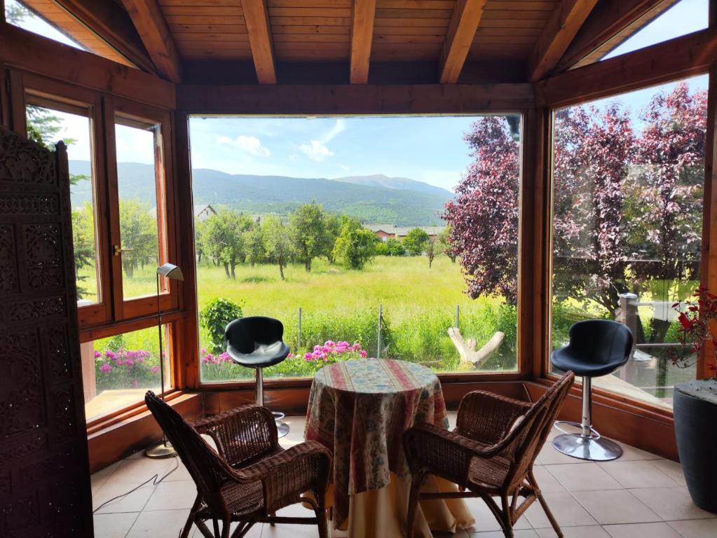 a room with a table and chairs and a large window at Los jardines de Osseja in Osséja