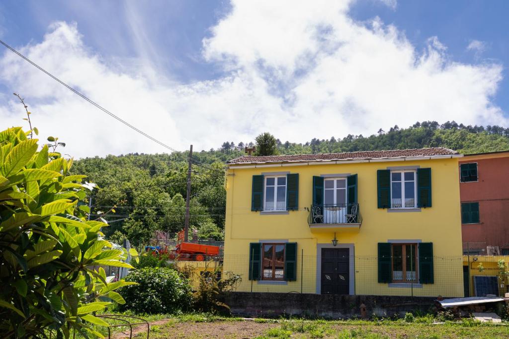 a yellow house with green shutters on a hill at Vita Lenta in Biassa