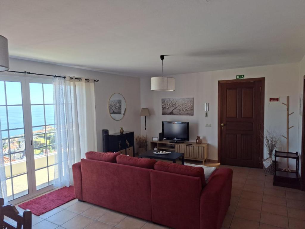 a living room with a red couch and a television at Pôr do Sol in Estreito da Calheta