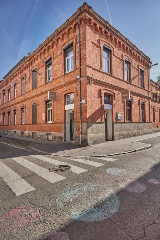 a red brick building on a street with a crosswalk at Appart'hôtel Odalys City - Toulouse Centre Gare in Toulouse