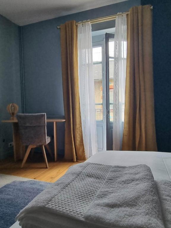 a bedroom with a bed and a window with a chair at Le Logis de Placide in Tarbes