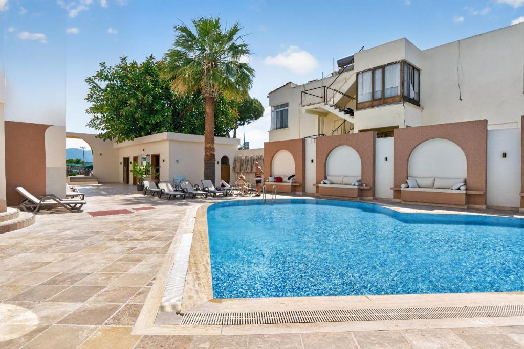 a swimming pool in front of a house with a palm tree at Mia Casa Hotel in Fethiye