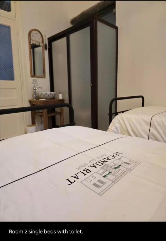 a white bed with a sign on top of it at LoCanda - Blat in Zahlé