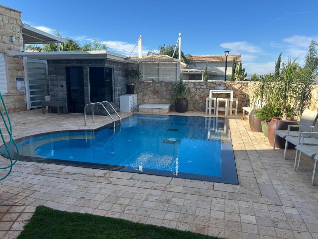 a swimming pool with blue water in a yard at Nofesh Ba Alon 10 in Rosh Pinna