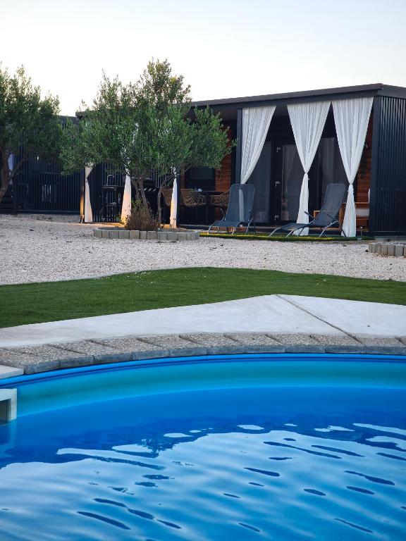 a swimming pool in front of a building with chairs at Rilux Mobile Home "Camping Pirovac" in Pirovac