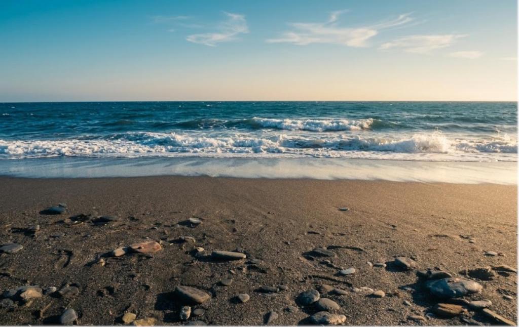 a beach with rocks in the sand and the ocean at Aguas de Mar in Castillo de BaÃ±os