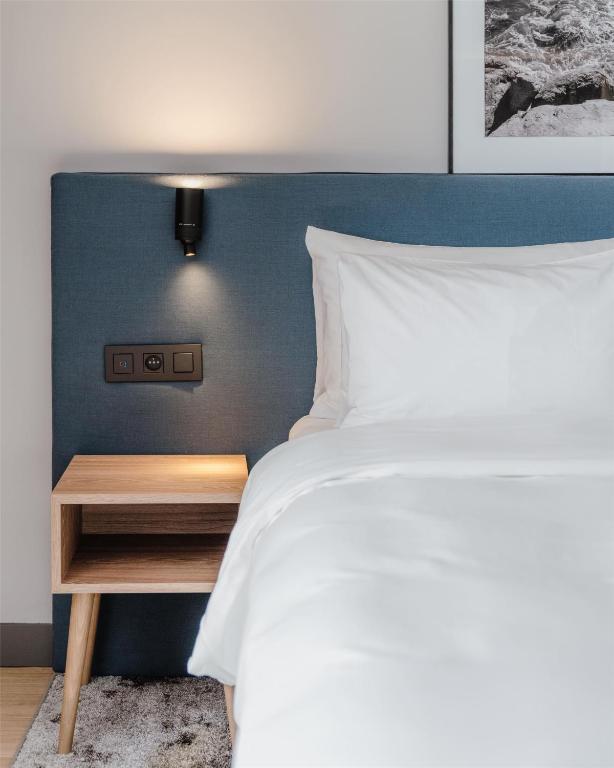 a bedroom with a white bed and a wooden night stand at Radisson Hotel Berlin Charlottenburg in Berlin