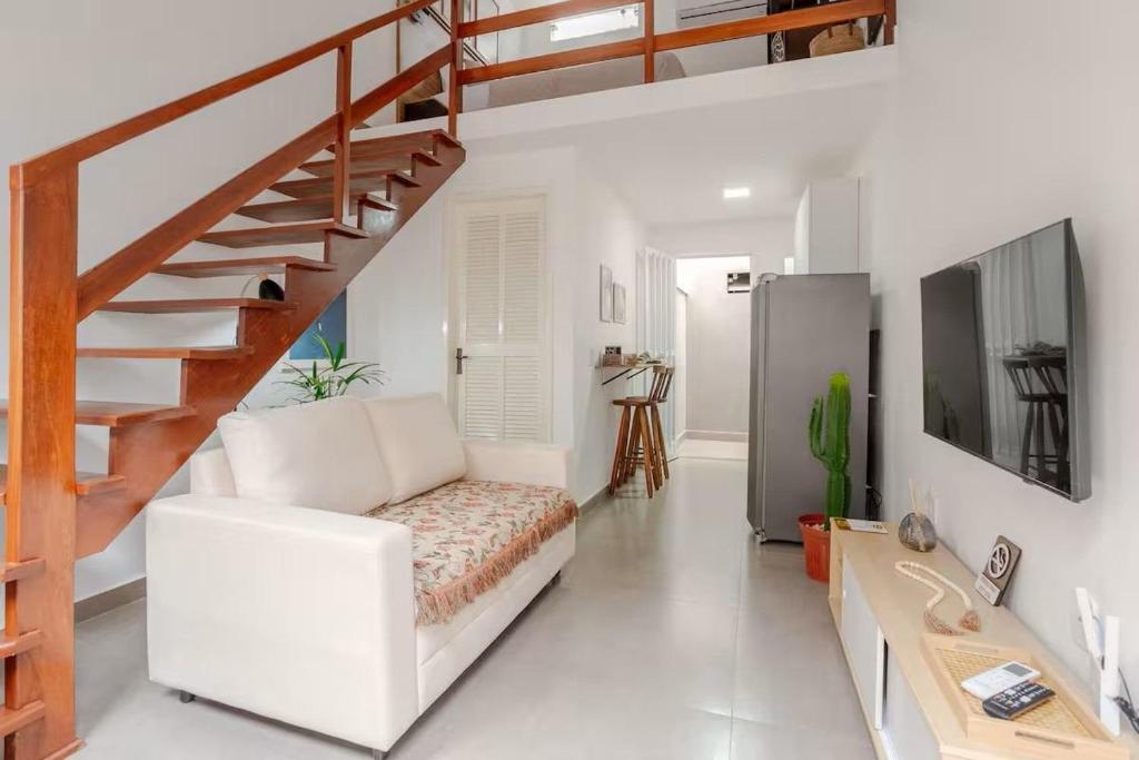 a living room with a white couch and stairs at Villa Bela - Lofts - cama queen e ar-condicionado in Iguaba Grande