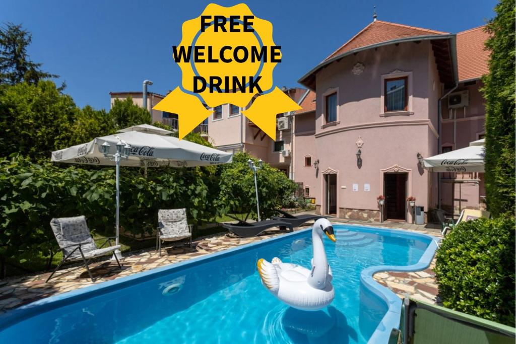 a swan in a swimming pool with a sign that reads free welcome drink at Illés Hotel in Szeged