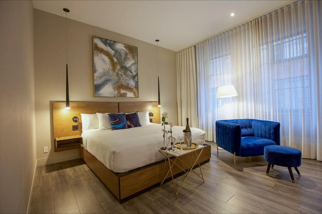 a bedroom with a bed and a blue chair at Hotel Royal William, an Ascend Collection Hotel in Quebec City