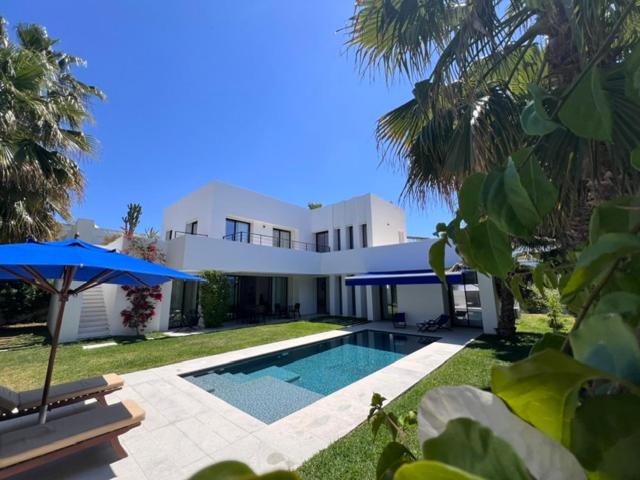 a large white house with a swimming pool and umbrella at Dar El Musc Chambres d'hôtes in Sukrah