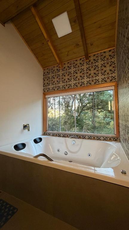 a large bath tub in a room with a window at Cabana Raízes da Mata - Hidro e Natureza in São Joaquim