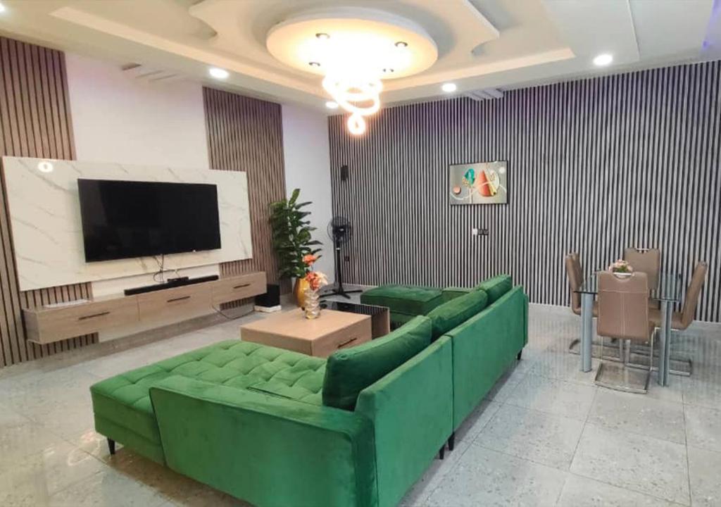 a living room with a green couch and a flat screen tv at SKYFORCE Bénin - Agatha in Porto-Novo