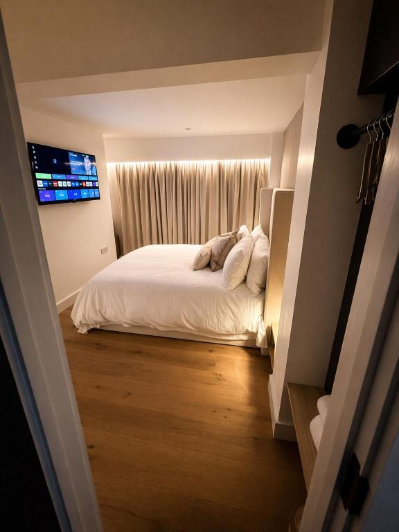 a bedroom with a white bed and a television at 1 Bridge Rd in Cranleigh