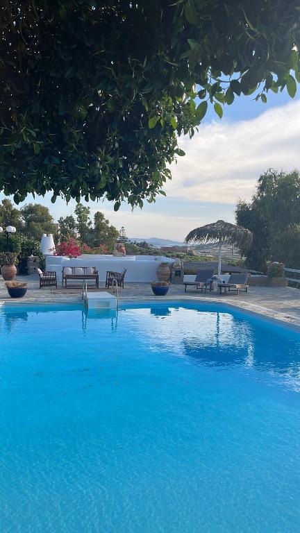 a large blue swimming pool with tables and chairs at Paros Casa Prive in Vrachonisída Loúmpinas