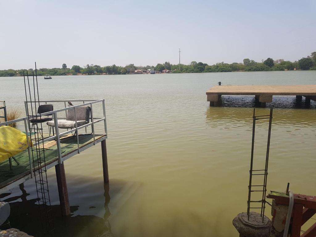 a dock on a body of water with a boat at baobolong ghuesthouse in Lamin Koto