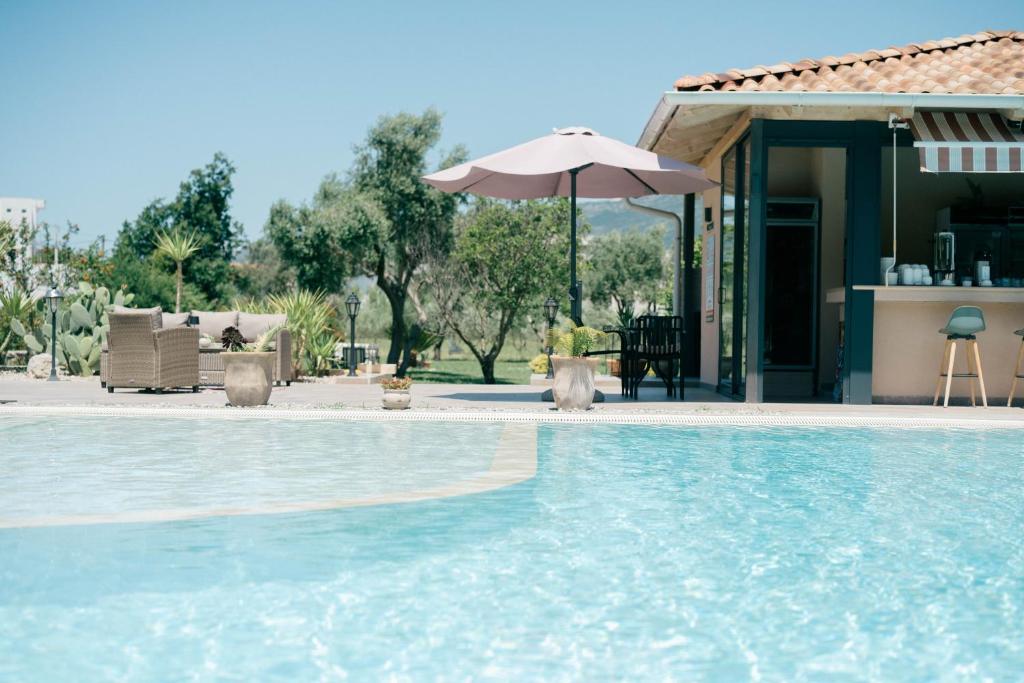 a swimming pool with an umbrella and a house at La Hacienda in Ulcinj