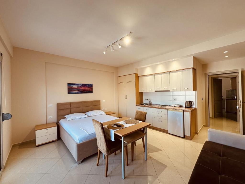 a bedroom with a bed and a table and a kitchen at Thoma's K Studios in Vlorë