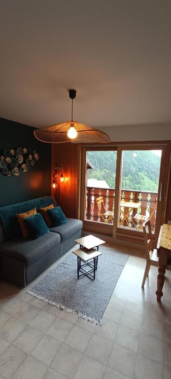 a living room with a couch and a table at Chez Nathalie - Appartement cosy- Multi pass offert- Draps, serviettes et ménage compris in Saint-Jean-d'Aulps