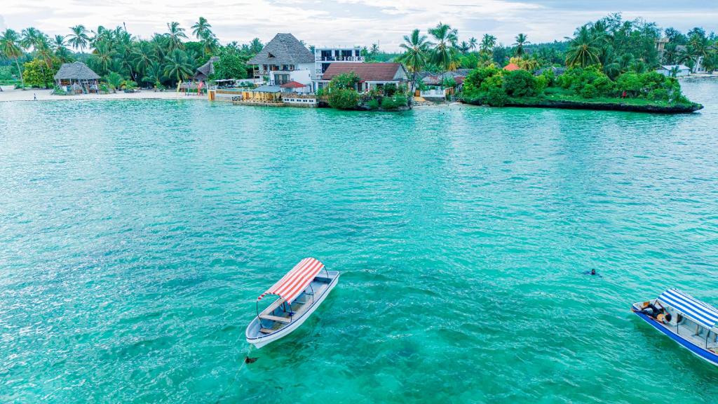 two boats in the water in front of a resort at Malcom Ocean View Retreat in Pongwe