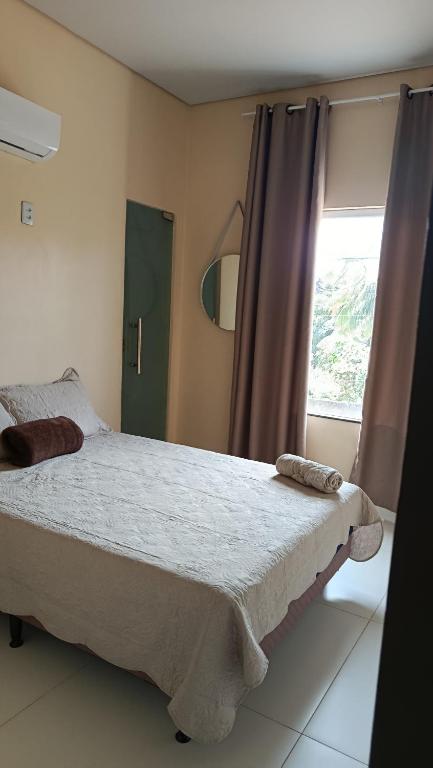 a bedroom with a large bed and a window at Suíte caripi in Barcarena
