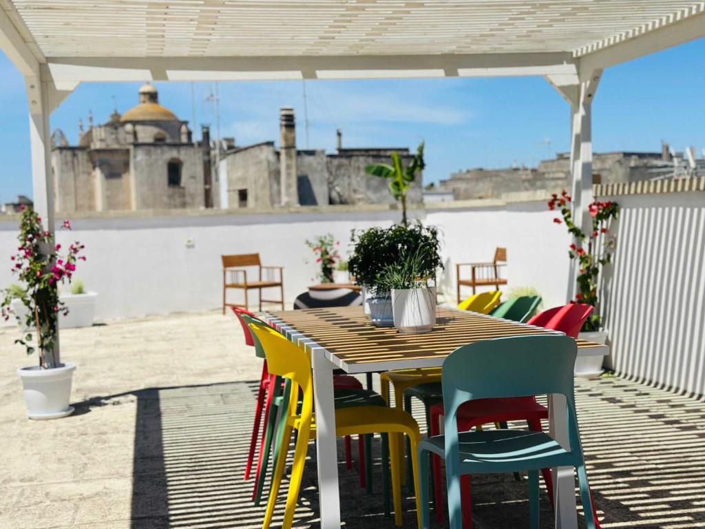 a wooden table with colorful chairs on a patio at BRIC à BRAC eclectic rooms in Uggiano la Chiesa