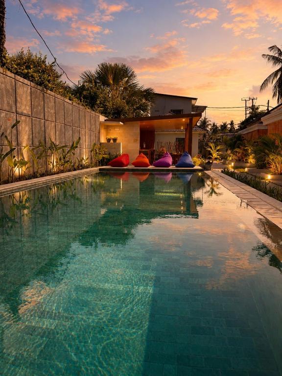 a swimming pool with colorful pillows on the side of a house at Qwank Kuta Lombok in Kuta Lombok