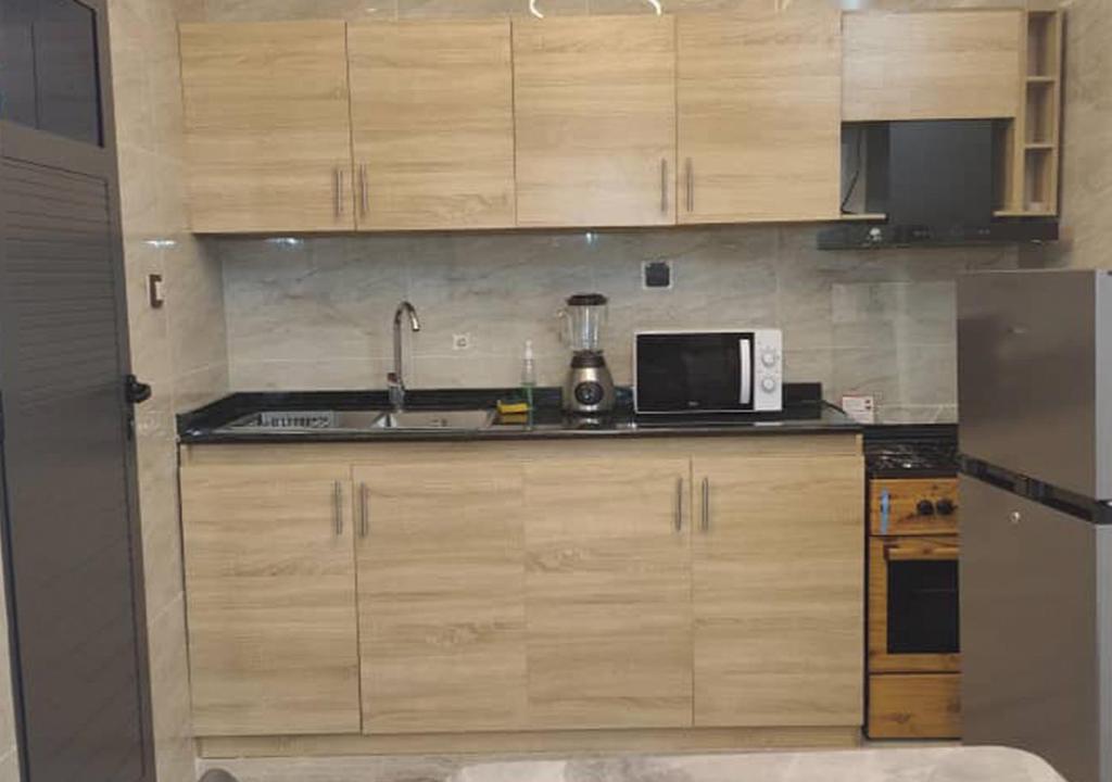 a kitchen with wooden cabinets and a microwave at STUDIO Meublée à Gbodjè in Porto-Novo