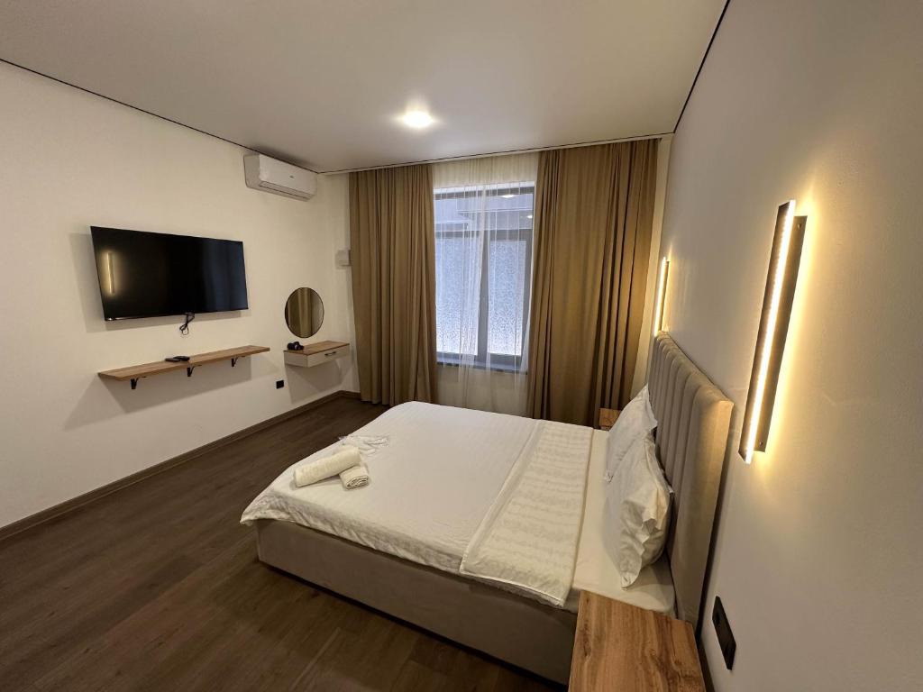 a hotel room with a bed and a flat screen tv at Gatsby Djal in Bishkek