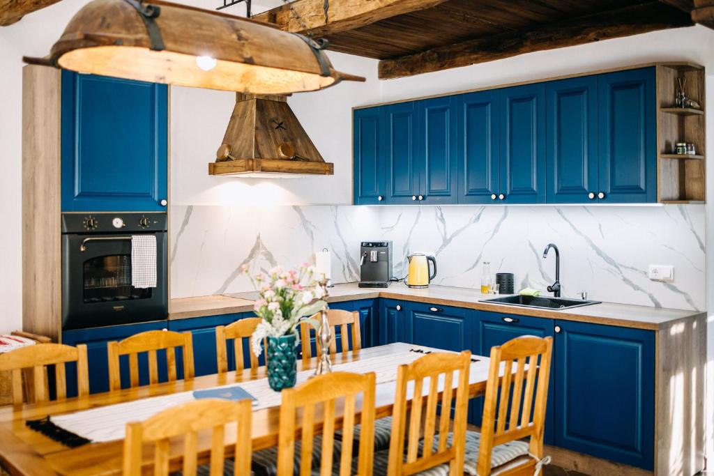 a kitchen with blue cabinets and a table with chairs at Demeter Guesthouse WOLF Siklod in Şiclod