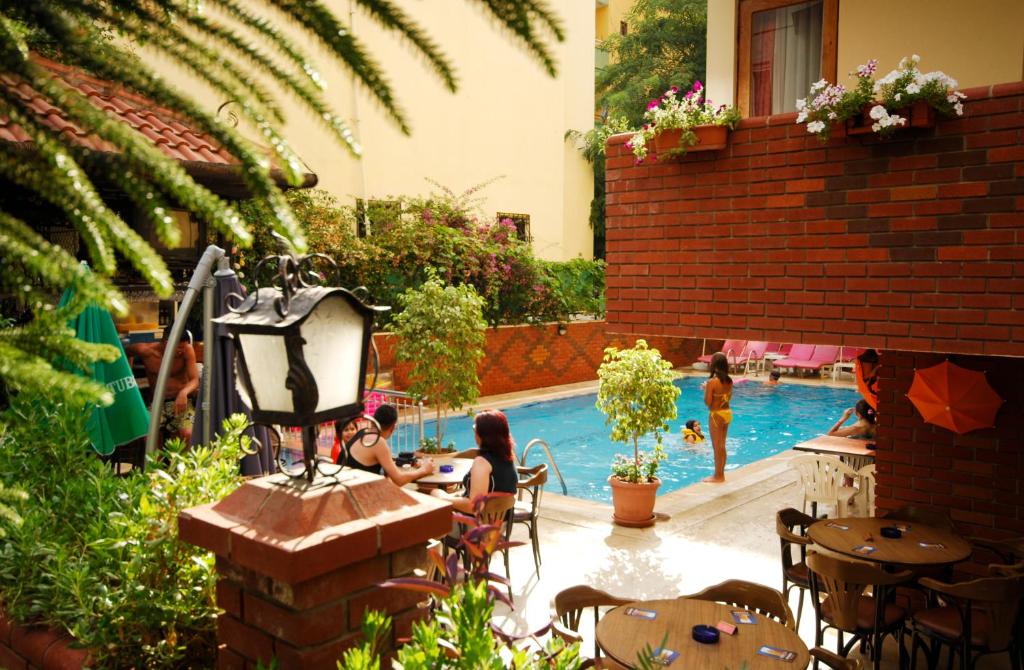 un grupo de personas sentadas en una mesa junto a una piscina en Bilkay Hotel, en Alanya