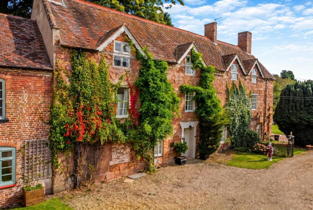 an old brick house with ivy on it at Historic 6-Bed Manor near Shifnal, Parking in Shifnal