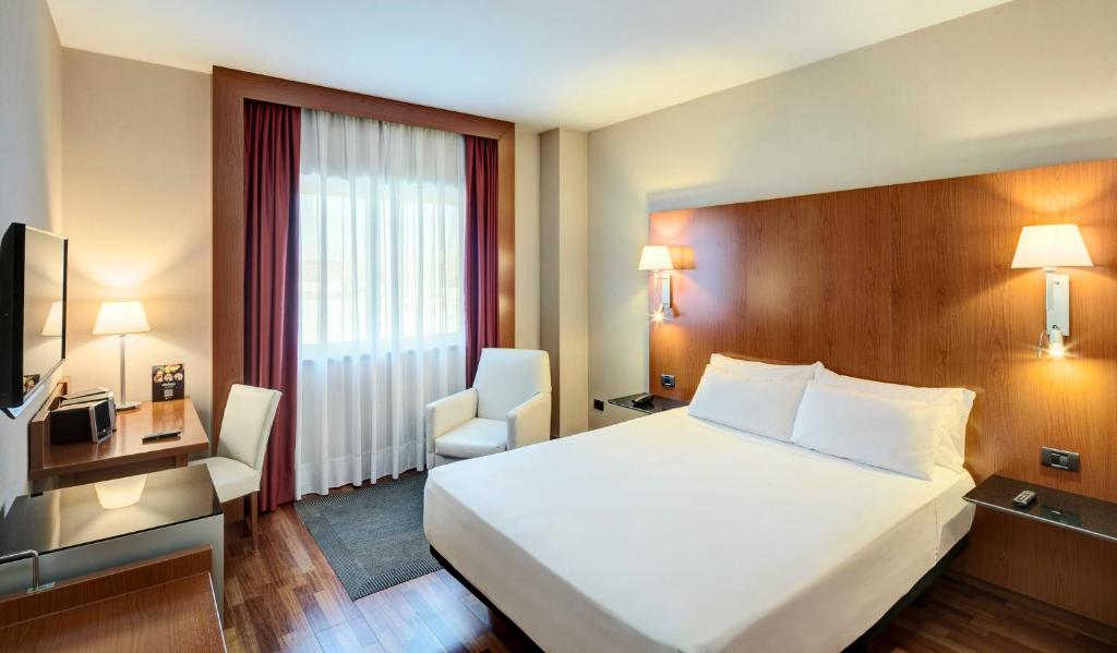 a hotel room with a large bed and a chair at Sercotel AB Rivas in Rivas-Vaciamadrid