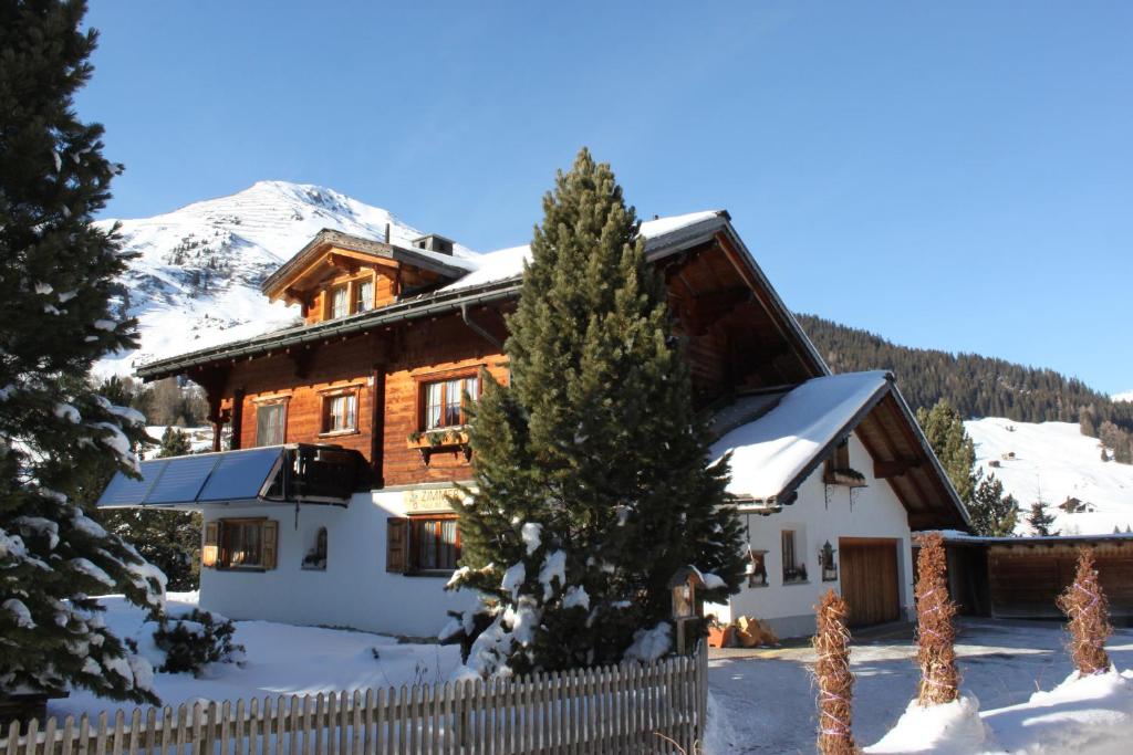 una casa de madera en la nieve con una valla en B&B Haus im Sand, en Davos