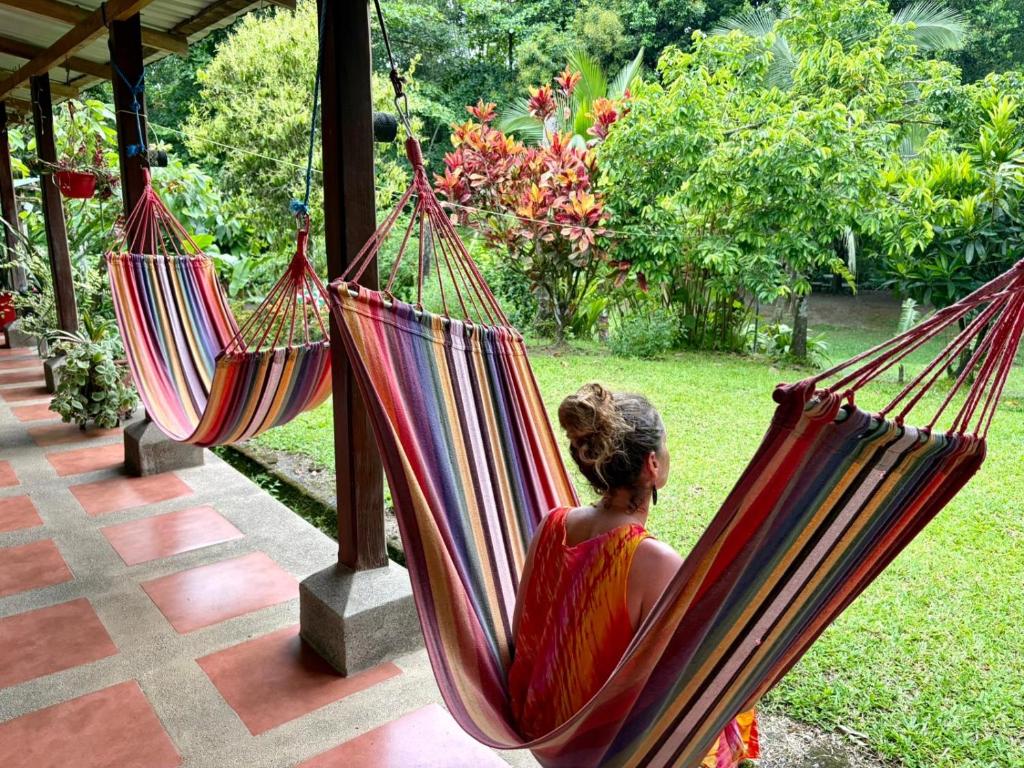 a woman sitting in two hammocks on a porch at RIVER SIDE LODGE in Horquetas