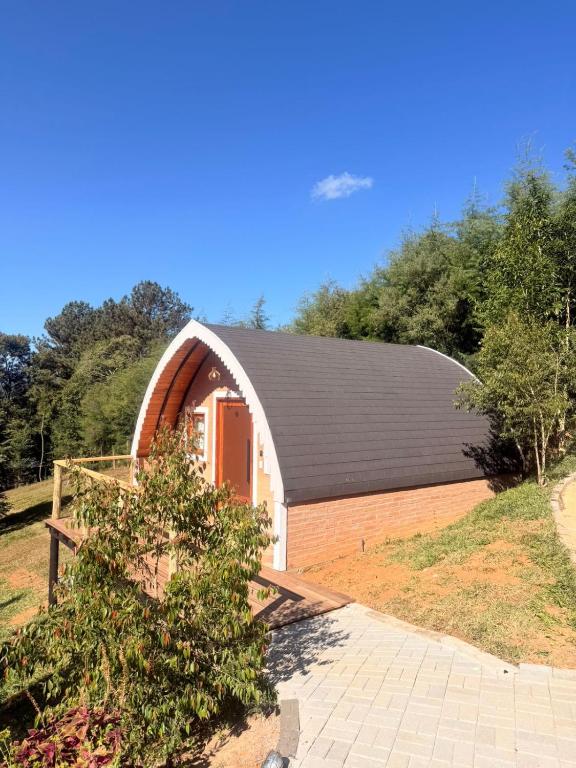 a barn with a black roof on a field at Recanto sol nascentre cabanas in Monte Verde