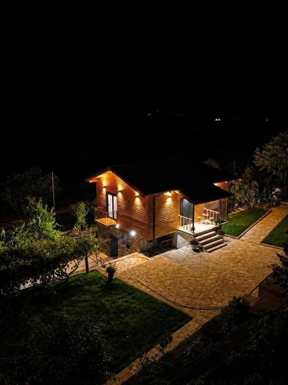 a small wooden house at night with lights at Guesthouse Deshnica in Këlcyrë